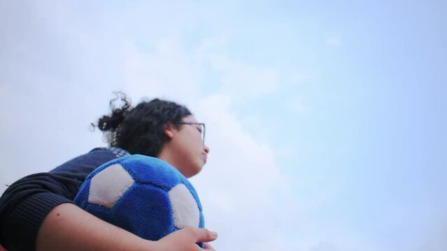 Woman holding blue soccer ball and using vuvuzela to support team in cloudy day	