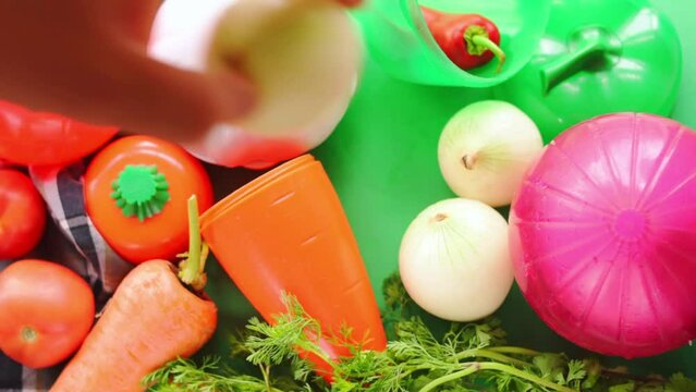 Hand taking vegetables and plastic vegetable shape storage containers from table