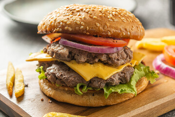 Homemade burger with two meats, cheese, lettuce, tomato and onion