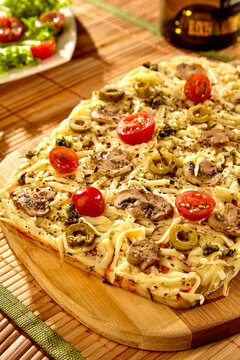 Delisiosa comida para compartir con la familia en una mesa de madera donde esta servida una exquisita fogazza de champi&ntilde;ones tomate y queso