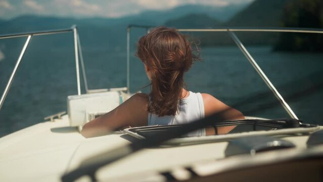 Relaxed woman with messy hair looks in distance on yacht bow