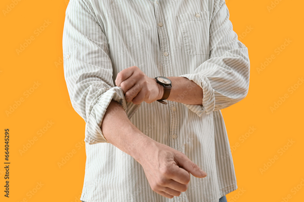 Wall mural Mature man rolling up his sleeve on yellow background, closeup - Wall murals