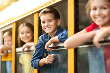 Excited children peeping from the school bus window
