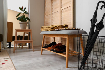 Bench with shoes, umbrellas and folding screen in hallway