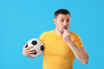 Male coach with soccer ball and whistle on blue background