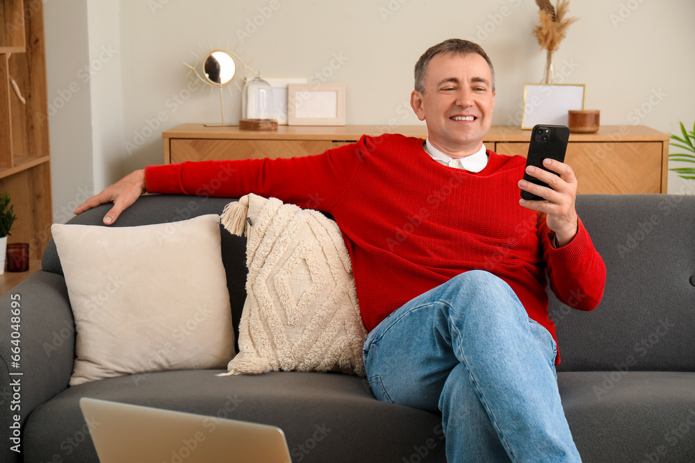 Poster Mature man with mobile phone messaging at home