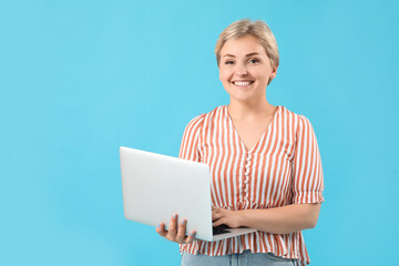 Happy young female programmer with laptop on blue background