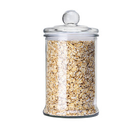 Oats in glass jar isolated on white background. Dry, uncooked oatmeal flakes