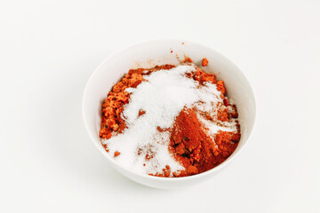 On the table in a plate there is a vegetable mixture covered with salt for preparing adjika.