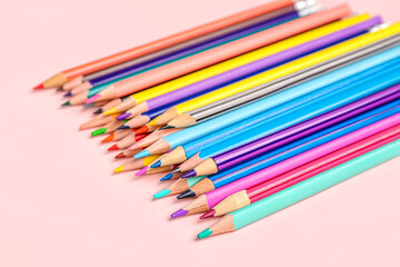 Heap of color pencils on pink background, closeup