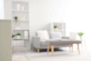 Blurred view of light living room with sofa and soft bench