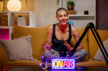 Caucasian bald woman recording a podcast while looking into the camera