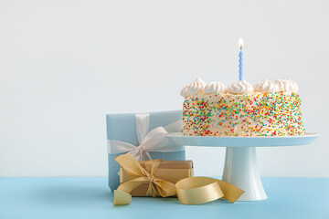 Stand with yummy Birthday cake and gift boxes on color background