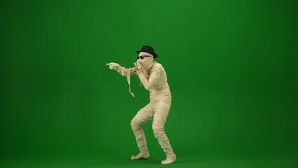 Green screen isolated chroma key photo capturing a mummy wearing sunglasses and a hat singing into...