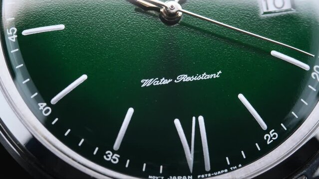 Stylish Luxury Man Wrist Watch With Moving Hand And Multiple Dials. Men's watch in metal with sapphire crystal. Closeup view of rotating watch, running second arrow. green dial. 