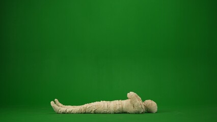 Green screen isolated chroma key photo capturing a mummy lying on the ground with its arms crossed...