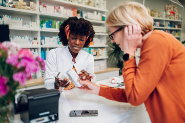 Obraz premium African american woman pharmacist selling drugs to a senior customer in a pharmacy