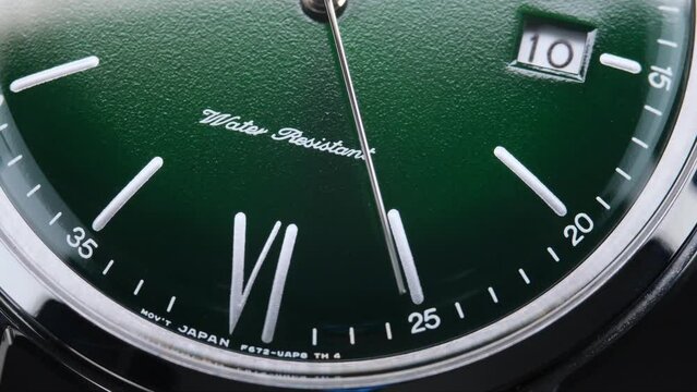 Stylish Luxury Man Wrist Watch With Moving Hand And Multiple Dials. Men's watch in metal with sapphire crystal. Closeup view of rotating watch, running second arrow. green dial. 