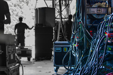 Backstage einer OpenAir Bühne mit Flycases und Kabelboxen, Kisten und Equipment im Betrieb und Techniker.