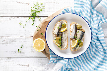 Sardines sandwiches on a white wooden background. Mediterranean food. Top view - obrazy, fototapety, plakaty