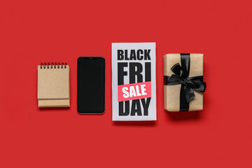 Black Friday sale greeting card with mobile phone, notepad and gift box on red background