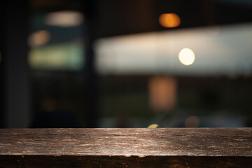 Empty dark wooden table in front of abstract blurred bokeh background of restaurant, window frames....