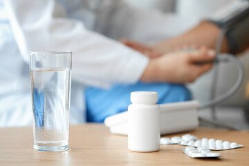 Glass of water with pills on table in room, closeup