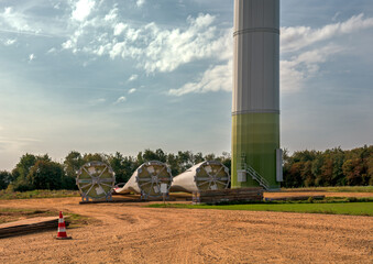 Installation of a wind turbine in the fields of Germany. Three fan blades lie on the ground to the...