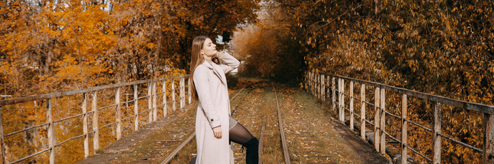 beautiful long-haired woman walks through the autumn streets. Railway, autumn, woman in a coat.