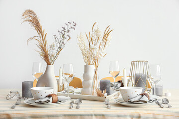 Elegant table setting with pampas grass, dried flowers and crockery in dining room