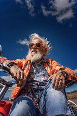 Old elderly man with tattoos riding on motorcycle down a road. White hair.