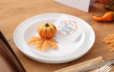 Festive table setting for Thanksgiving Day with greeting card, pumpkin and leaf, closeup