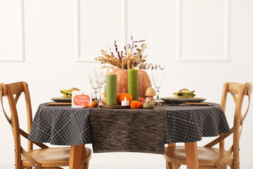 Festive table setting for Thanksgiving Day with pumpkins, greeting card and burning candles