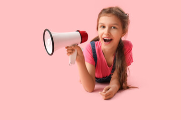 Little girl with megaphone lying on pink background