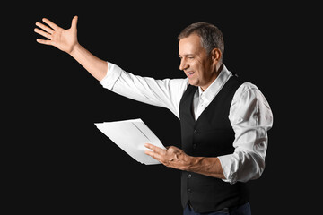 Mature actor reading film script on dark background