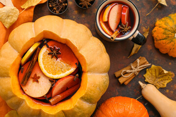 Beautiful composition with tasty mulled wine in pumpkin on brown background