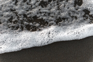 A wave runs aground on a brown sand beach