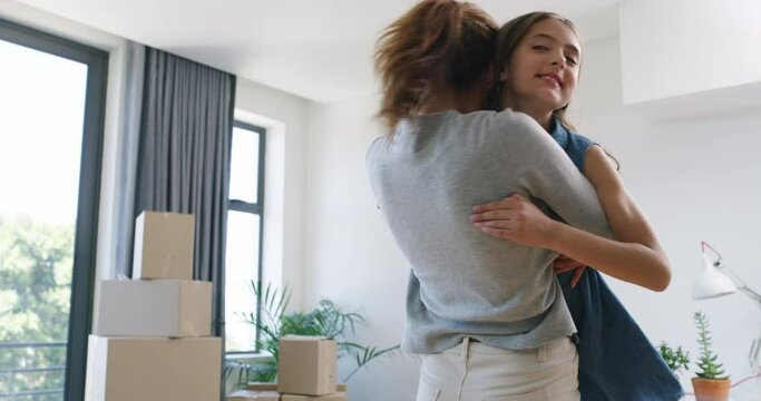 Moving to new home, mom and daughter hug with smile, boxes and love in living room. Real estate, security and happy woman in embrace with excited child in apartment together with future investment