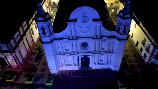 Cinematic aerial dolly shot over an antique cathedral in Santa Rosa de Copan, Honduras, and that is illuminated with blue light