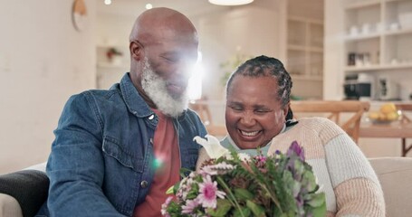 Sofa, flowers and love with a senior black couple in their home living room for anniversary celebration. Birthday, valentines day and an elderly husband hugging his wife while laughing for romance - Powered by Adobe