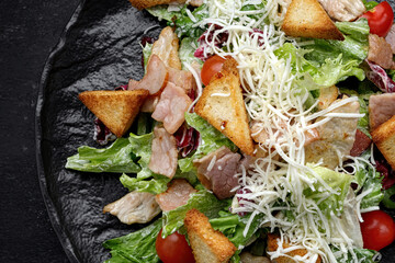 Caesar salad on a black plate. Horizontal