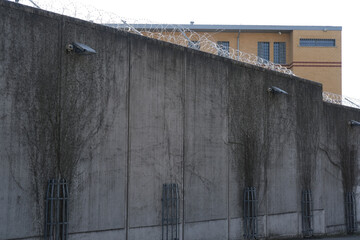 high concrete fence, barbed wire fence on top, building for execution of punishments for criminals,...