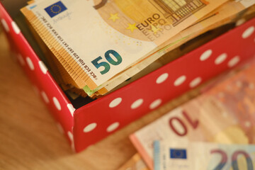 close-up box with family savings, cash 50, 20 euro banknotes on table, concept gift for holiday,...