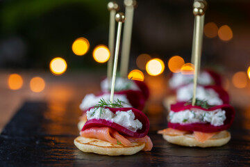 Christmas canapes with blinis with salmon, pickled beetroot and goat cheese