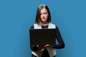 Young woman using laptop computer, on blue background
