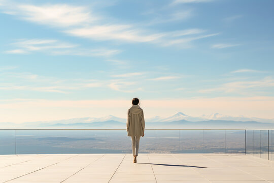a woman gazes at the horizon to the mountains from a terrace