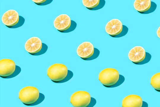 Trendy Summer food pattern made with yellow lemon on bright light blue background. Whole and sliced lemons. Minimal summer concept. © Ivan