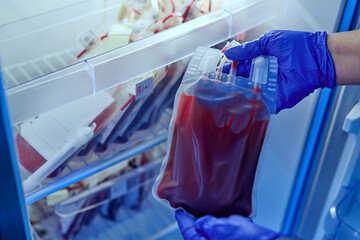doctor holding a bag of red blood in the blood storage refrigerator in the laboratory of the blood...