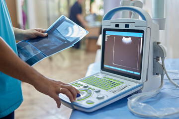 doctor holding x-ray scan in hospital room near ultrasound machine, mobile ultrasound machine,...