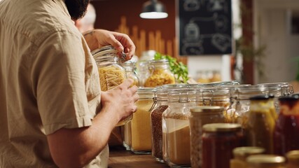 Vegan man in zero waste supermarket using decomposable paper bag while shopping for organic pantry staples. Customer in local neighborhood shop with no single use plastics policy, close up